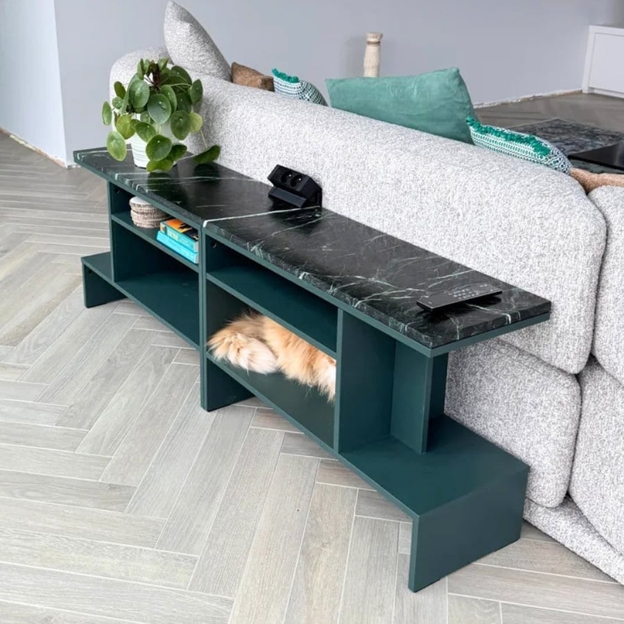 IKEA HOLMERUD Green marble-top console table beside a gray sofa; plant on the left, remote on top, and a fluffy cat curled in the bottom shelf.
