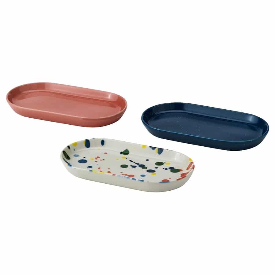 Set of three oval ceramic serving dishes in pink, navy blue, and speckled white with colorful dots, suitable for appetizers or sides.