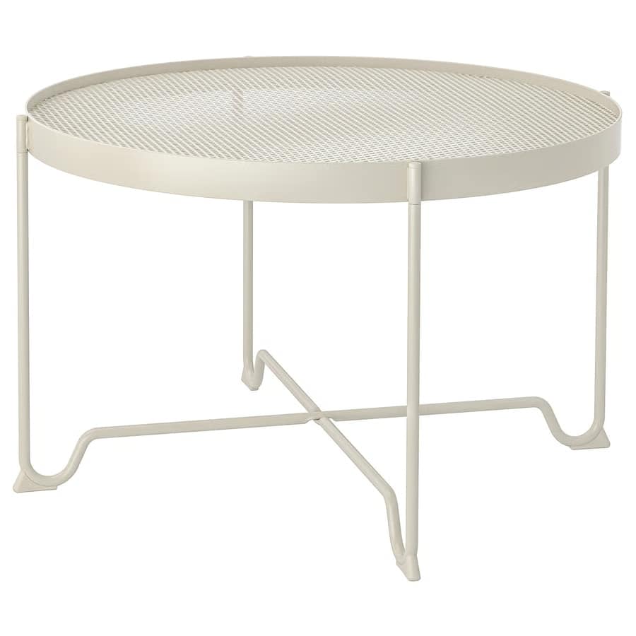 Round cream metal fire pit with a mesh grate on four slender legs for outdoor patio use.