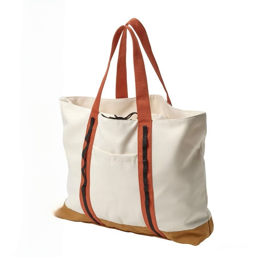 Beige canvas tote bag with orange straps and a brown bottom, standing upright on a white background at an angle.