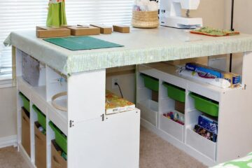 Bright sewing/craft corner with a white worktable, green curtains, and a sewing machine on top; organized storage underneath.