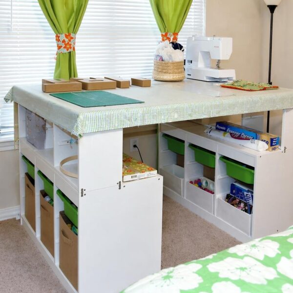 Bright sewing/craft corner with a white worktable, green curtains, and a sewing machine on top; organized storage underneath.