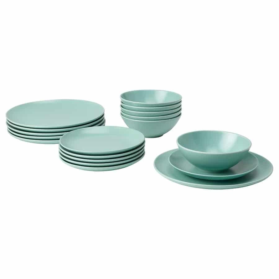 Turquoise dinnerware set with stacked plates and bowls arranged on a white background.