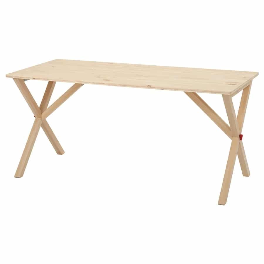 Wooden workbench with a rectangular natural wood top and two X-shaped trestle legs in a workshop-style setup.