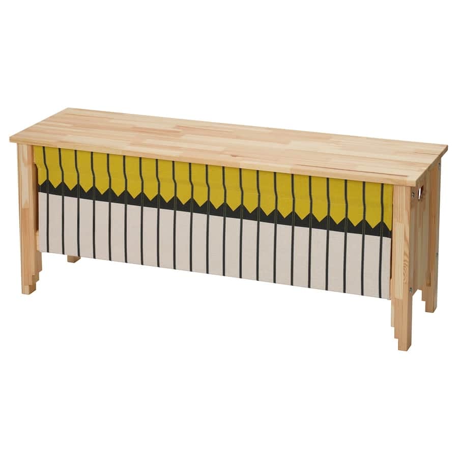 6 - IKEA Hackers Long wooden workbench with a row of yellow and gray woven strips hanging along the front, like a weaving loom display.