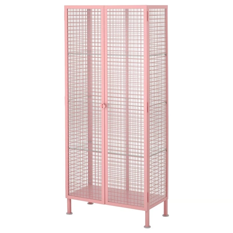Tall pink metal mesh storage cabinet with two hinged doors and four legs, suitable for shelving small items