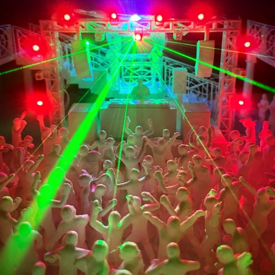 Front view of mini rave coffee table showing a crowded, red-lit space with many people along the glass walls and a few green light spots in the center.