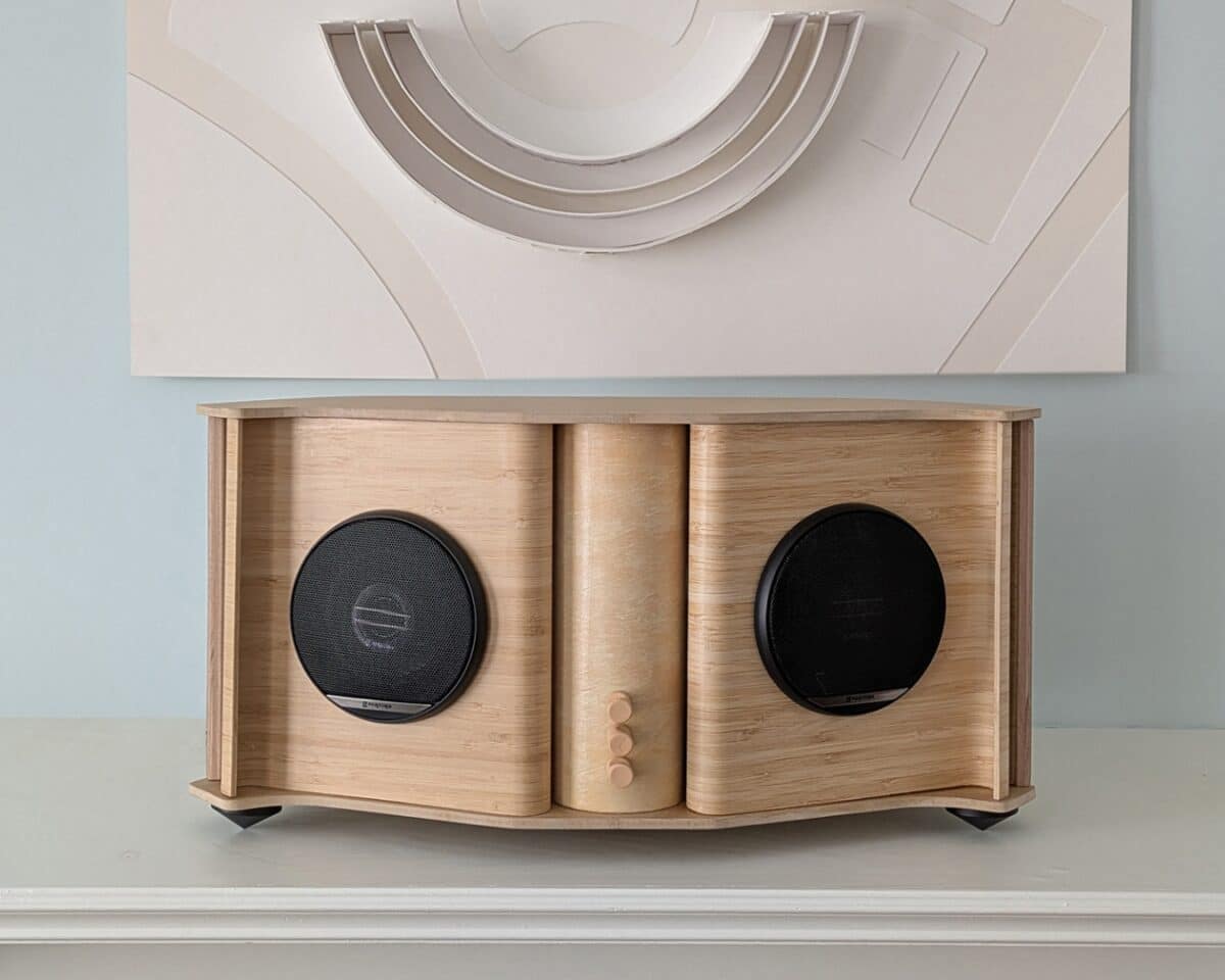 1 - IKEA Hackers DIY speaker stereo cabinet with a central cylindrical column and round black drivers on each side, placed on a mantel with abstract art above.