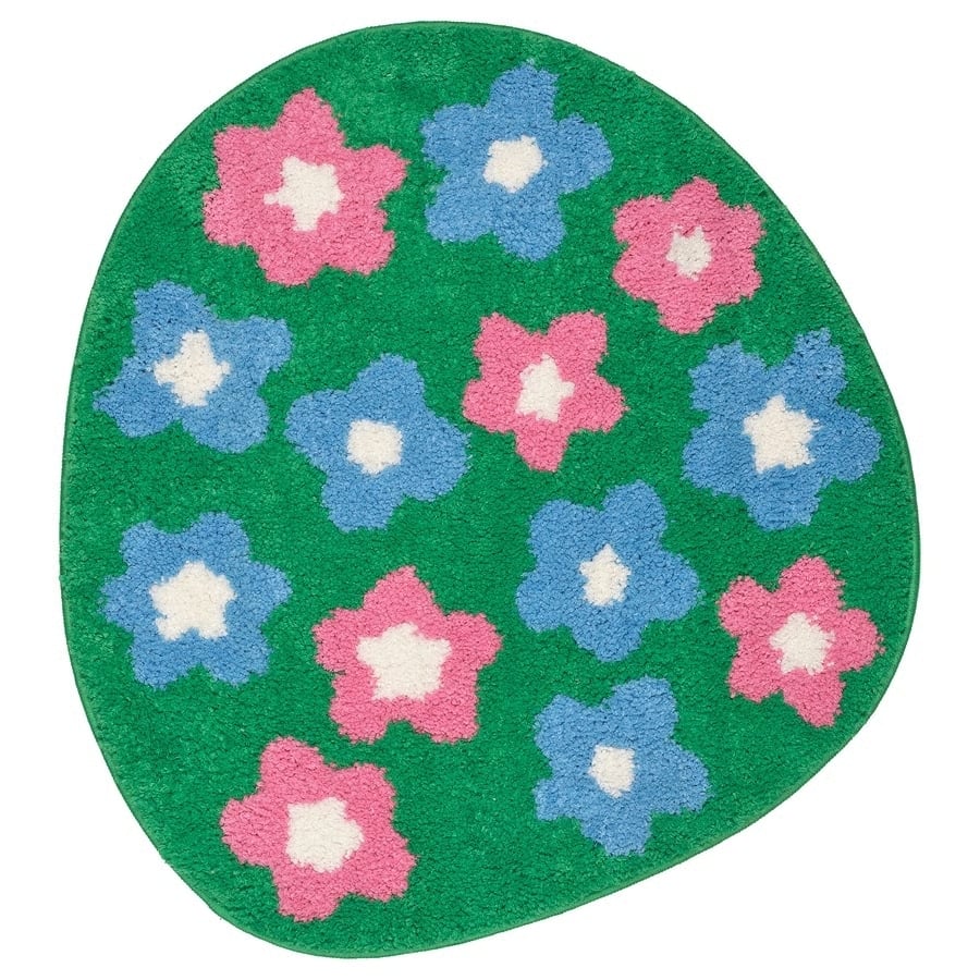 Round green rug with pink and blue flower patterns and white centers, decorative floor mat for kids' rooms or play areas.
