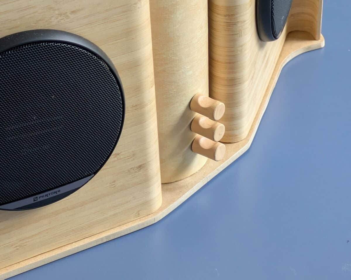 13 - IKEA Hackers Wooden speaker system with cylindrical columns and three wooden pegs on a curved base against a blue surface.