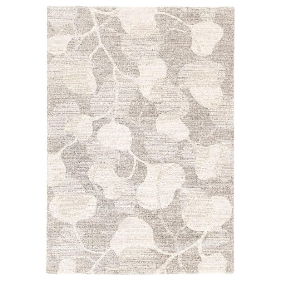 Neutral beige area rug with an abstract cream leaf pattern across the surface.