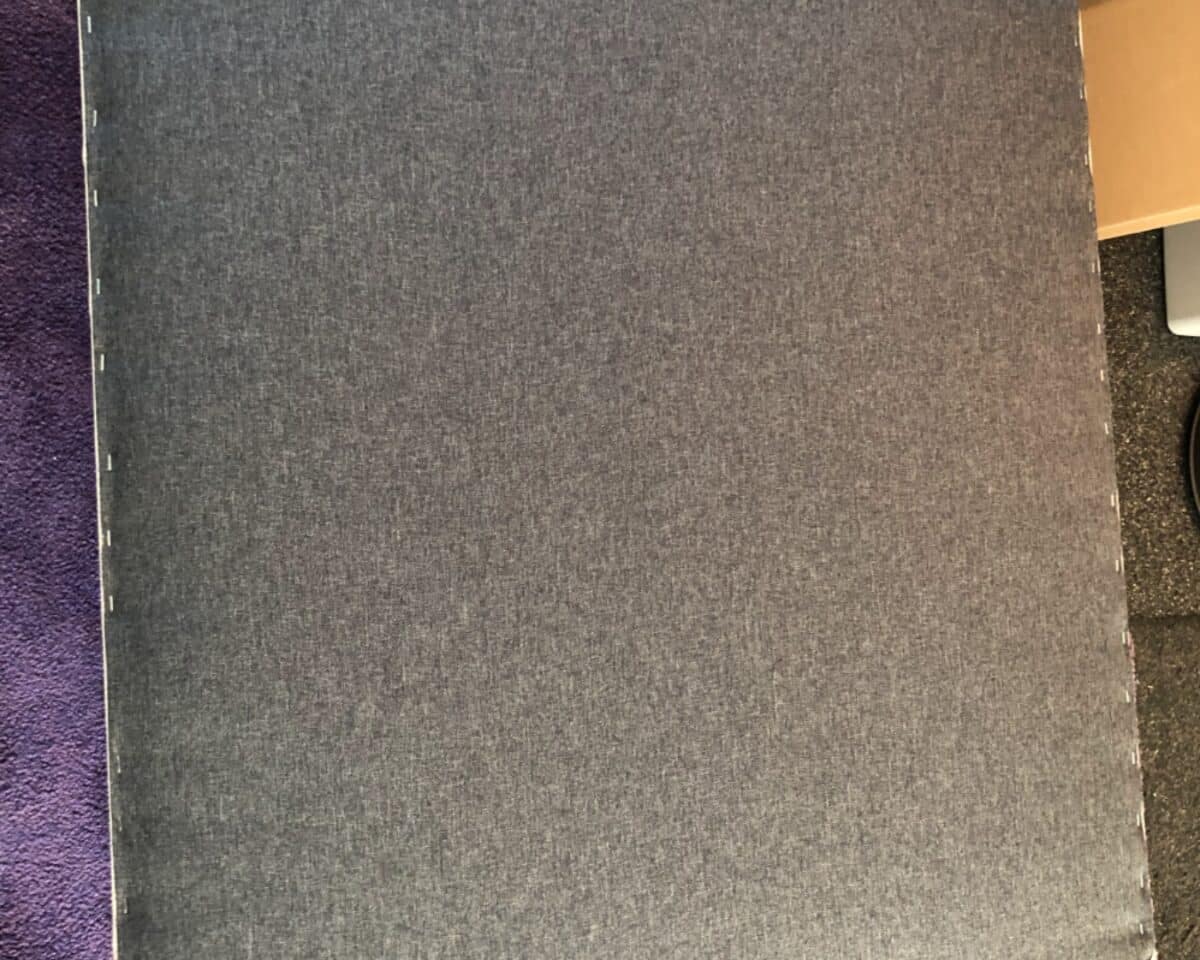 Top-down view of a dark gray fabric-covered binder with visible white stitching along the left edge.