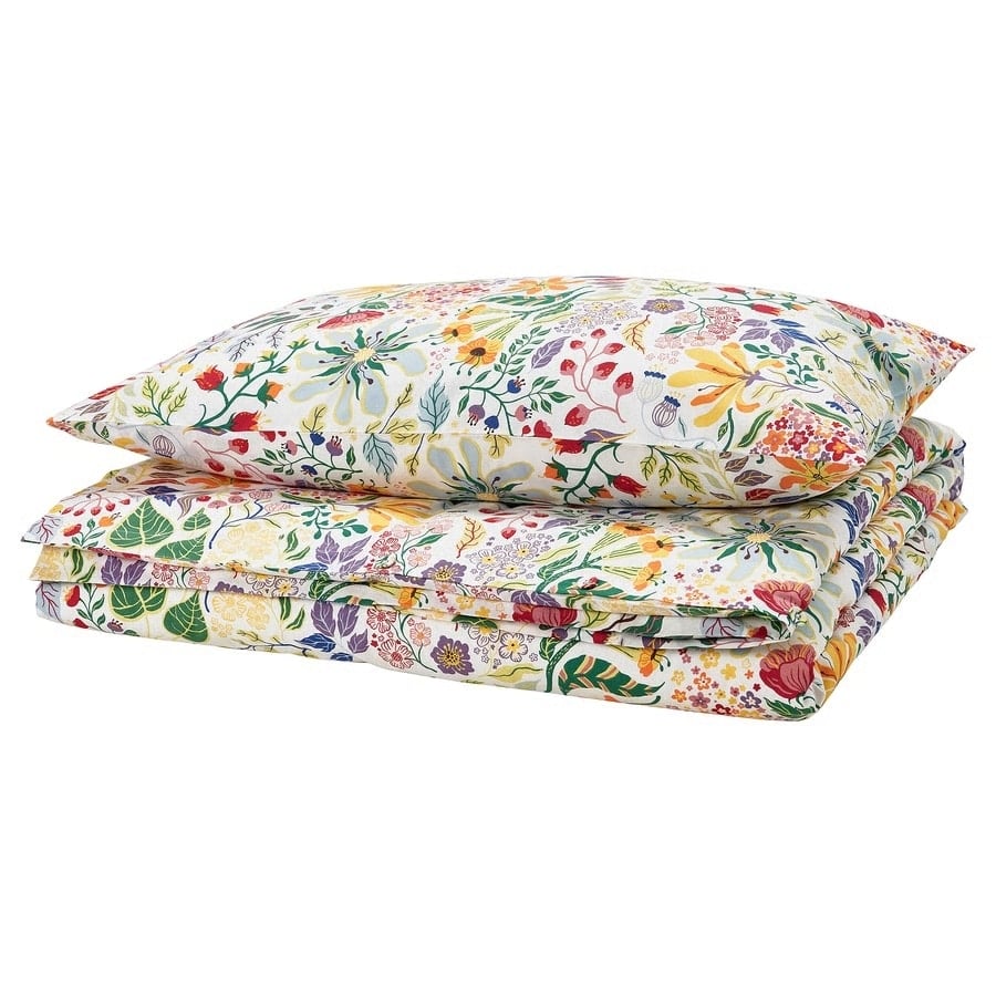 Stack of floral-patterned bedding including a pillow and quilted duvet cover on top of folded sheets/comforter. (informative)