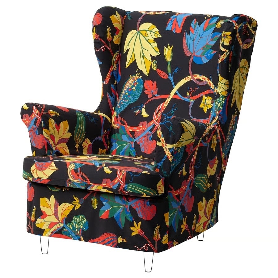 Wingback armchair with a bold multicolor floral pattern on a black background.