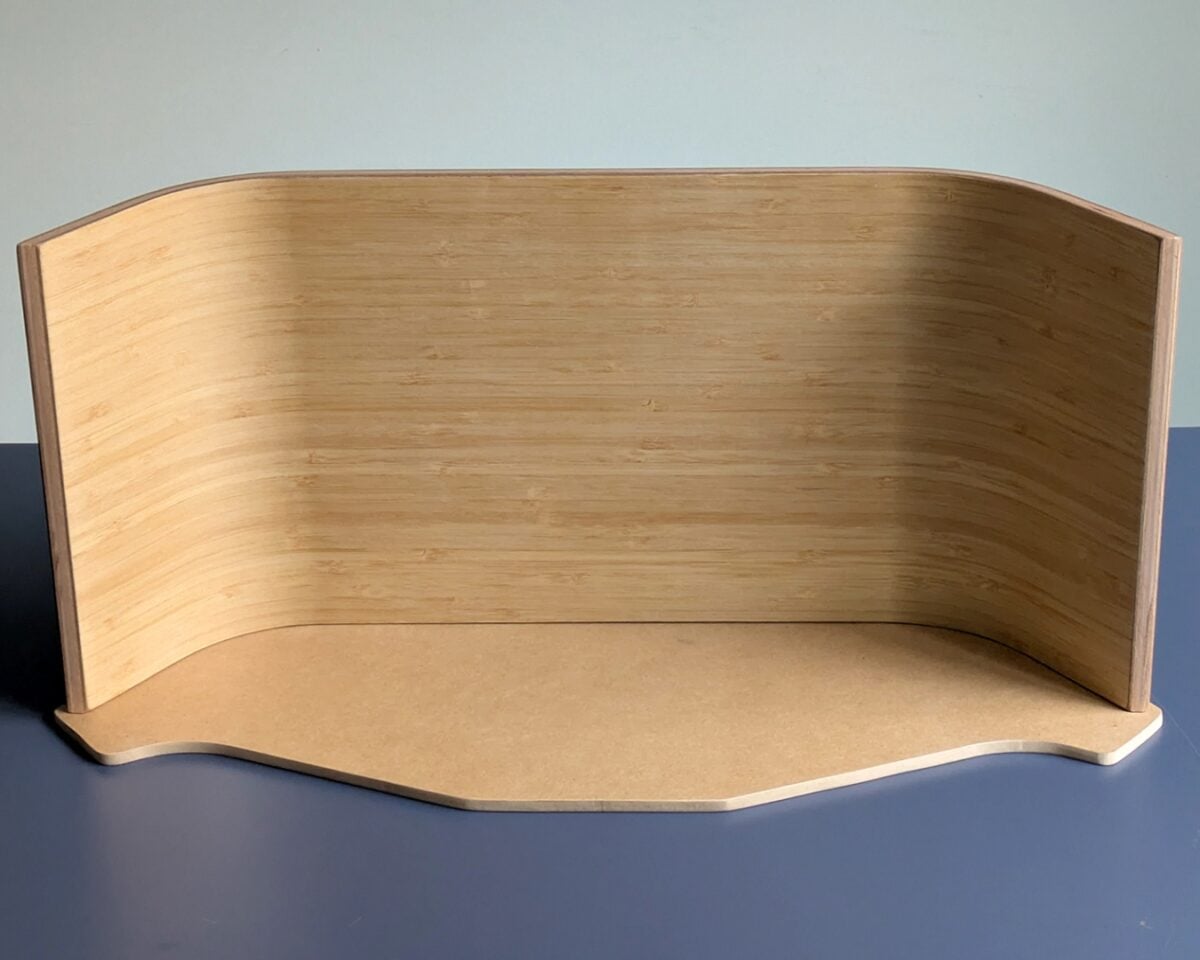 6 - IKEA Hackers Light wood curved desk divider with a rounded base sits on a blue surface.