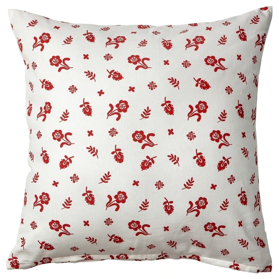White decorative throw pillow with a scattered red floral pattern on a white background.