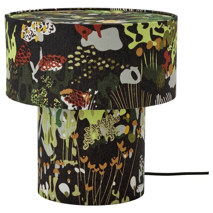 Colorful abstract-patterned fabric table lamp with a cylindrical base and drum shade in green, black, and orange tones.