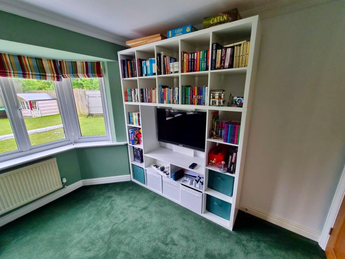 kallax lappland tv unit 2 - IKEA Hackers White modular bookshelf surrounding a flat-screen TV in a green-carpeted living room, with a window and striped blinds to the left.