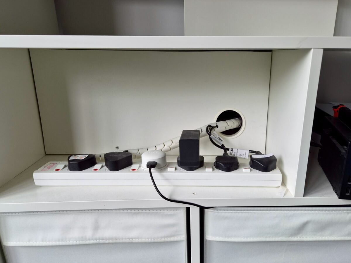 kallax lappland tv unit 3 - IKEA Hackers White power strip with multiple plugs and adapters on a shelf, cables routed through a circular back panel opening.