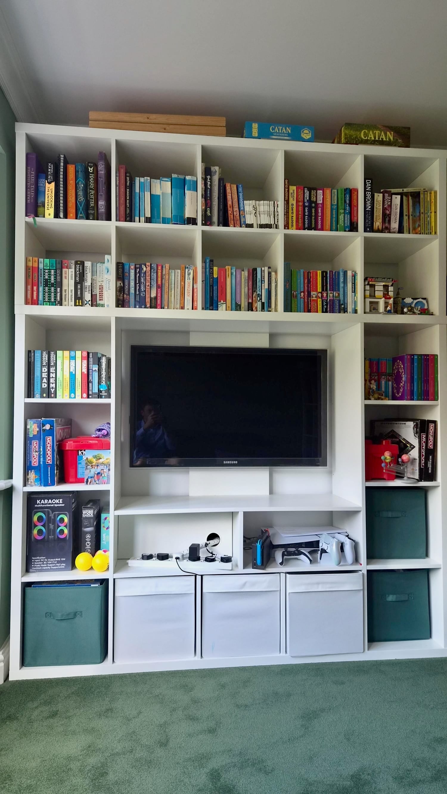 IKEA KALLAX LAPPLAND IKEA KALLAX LAPPLAND playroom storage and TV combo hack. white modular shelving unit filled with colorful books surrounding a mounted TV and small toy/set pieces on the right shelf area.