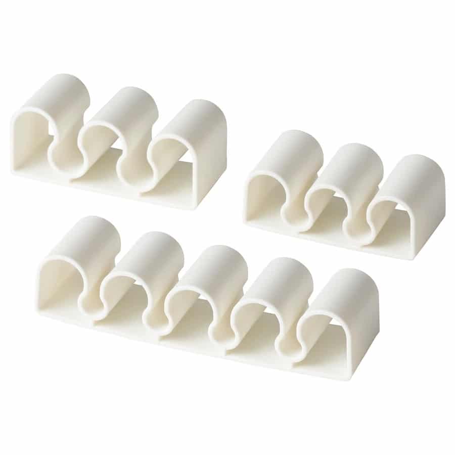 15 - IKEA Hackers KALKSTUFF Cable Holder - White plastic cable organizer with multiple curved channels on a base, designed to hold and separate several cords in one strip