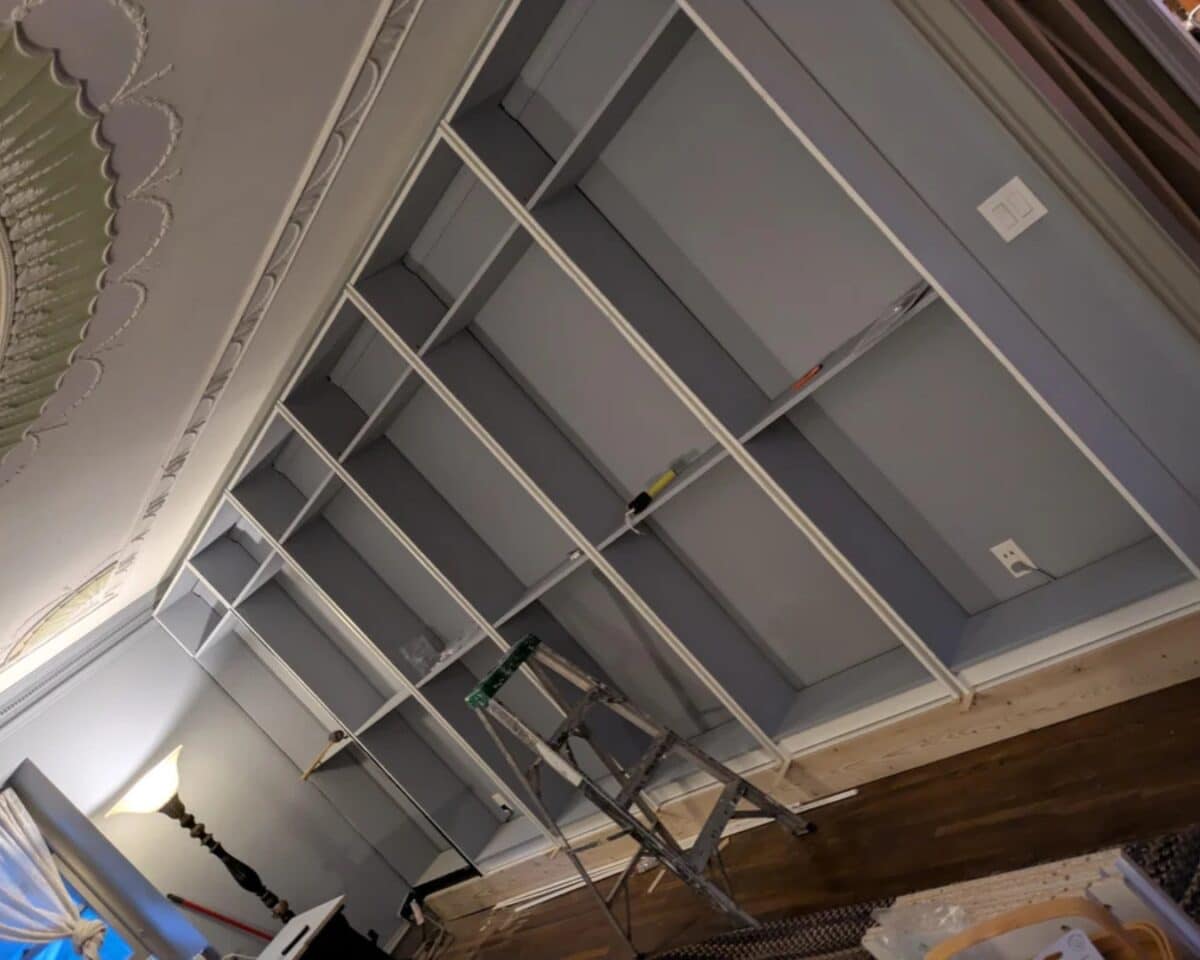 Unfinished BILLY bookcases and a ladder in a living room during renovation.