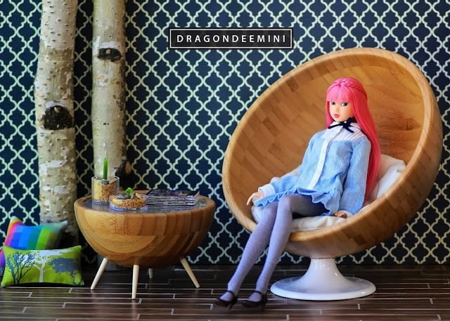 IMG_5215-776699 - IKEA Hackers Fashion doll with pink hair lounging in a round wooden chair, in a stylish patterned room with a snack table nearby.
