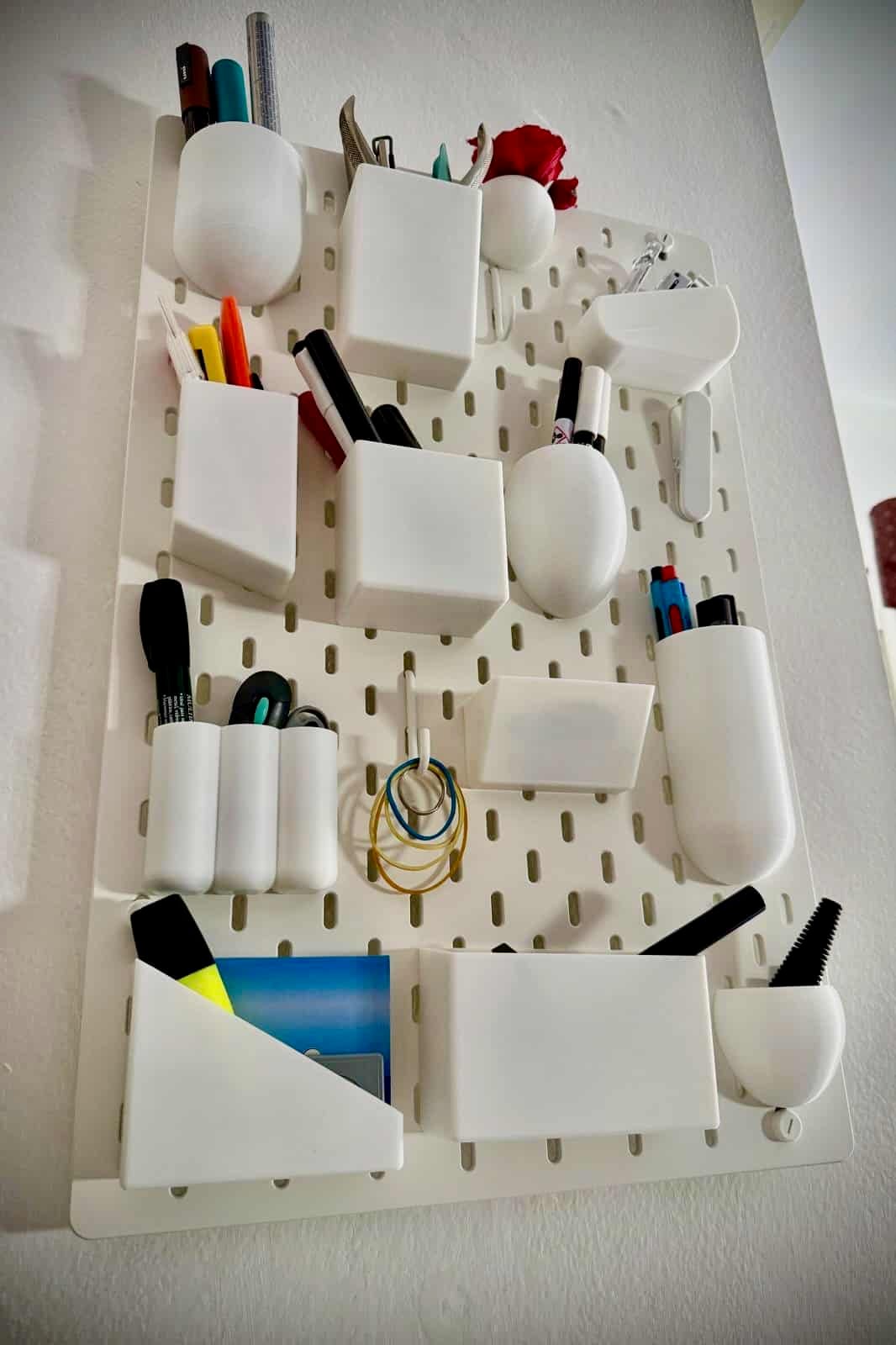 UtenSkadis 1 - IKEA Hackers IKEA SKÅDIS pegboard UTEN wall organizer inspired hack. White modular wall organizer with cups and boxes holding markers, scissors, and rings viewed from above (storage system)