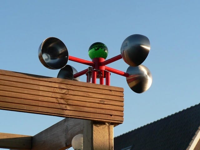 anemometer3-757055 - IKEA Hackers Anemometer with four metallic cups on a red frame atop a wooden beam against a clear blue sky, green center globe visible.