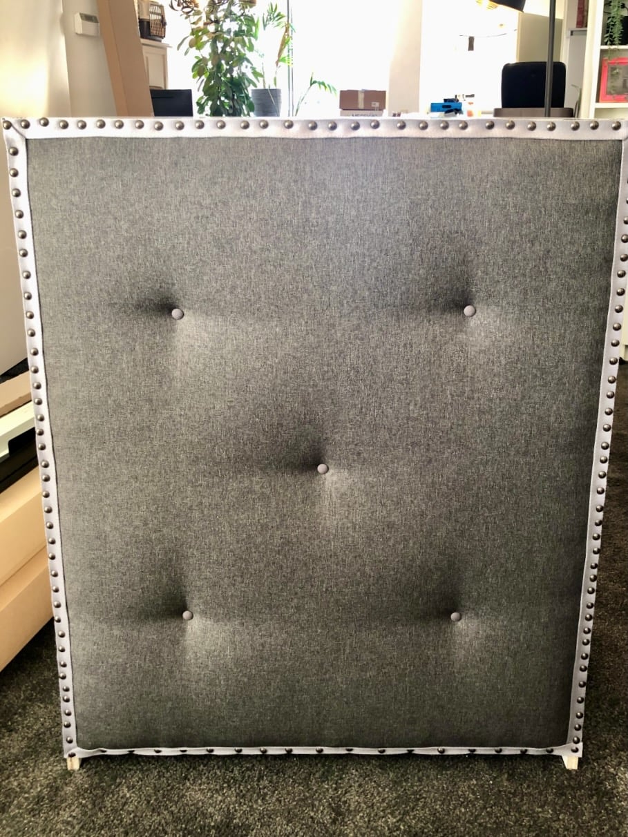 IKEA MALM chest with grey upholstered panel with silver nailhead trim and button tufting along the border, standing upright. To serve as room divider or placed in the middle of room.