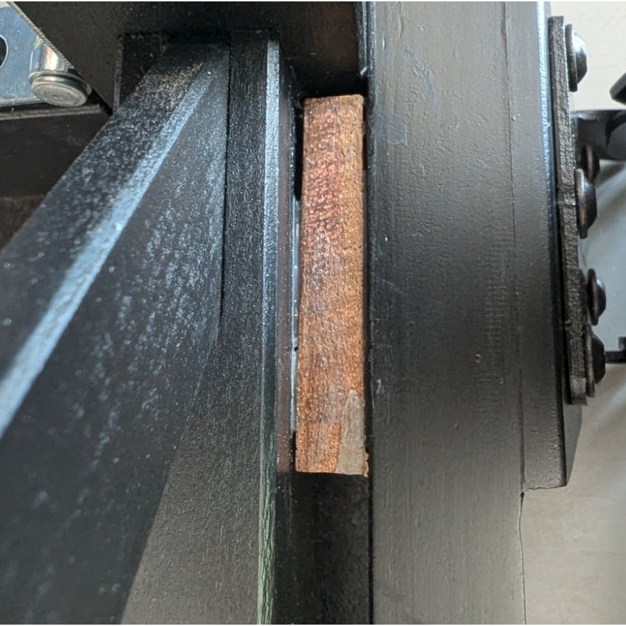 22 - IKEA Hackers Rusty rectangular metal shim wedged between two black vise jaws in a machine setup.