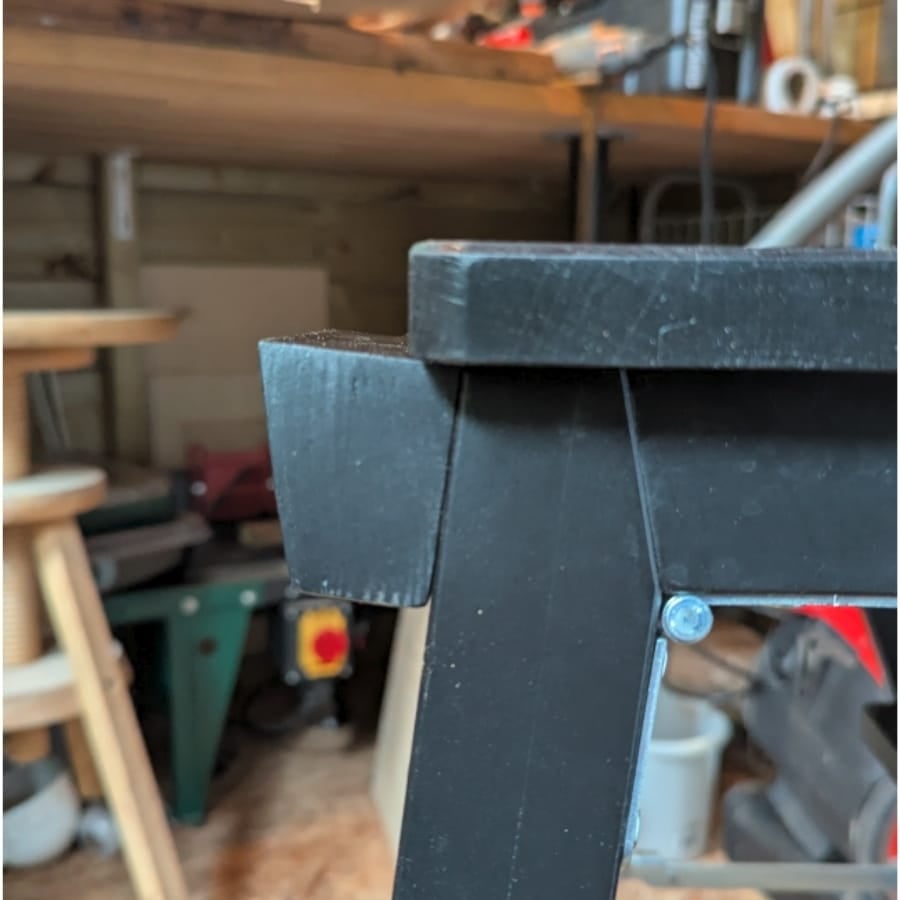 25 - IKEA Hackers Close-up of a black metal frame corner with a bolt, in a woodworking workshop.