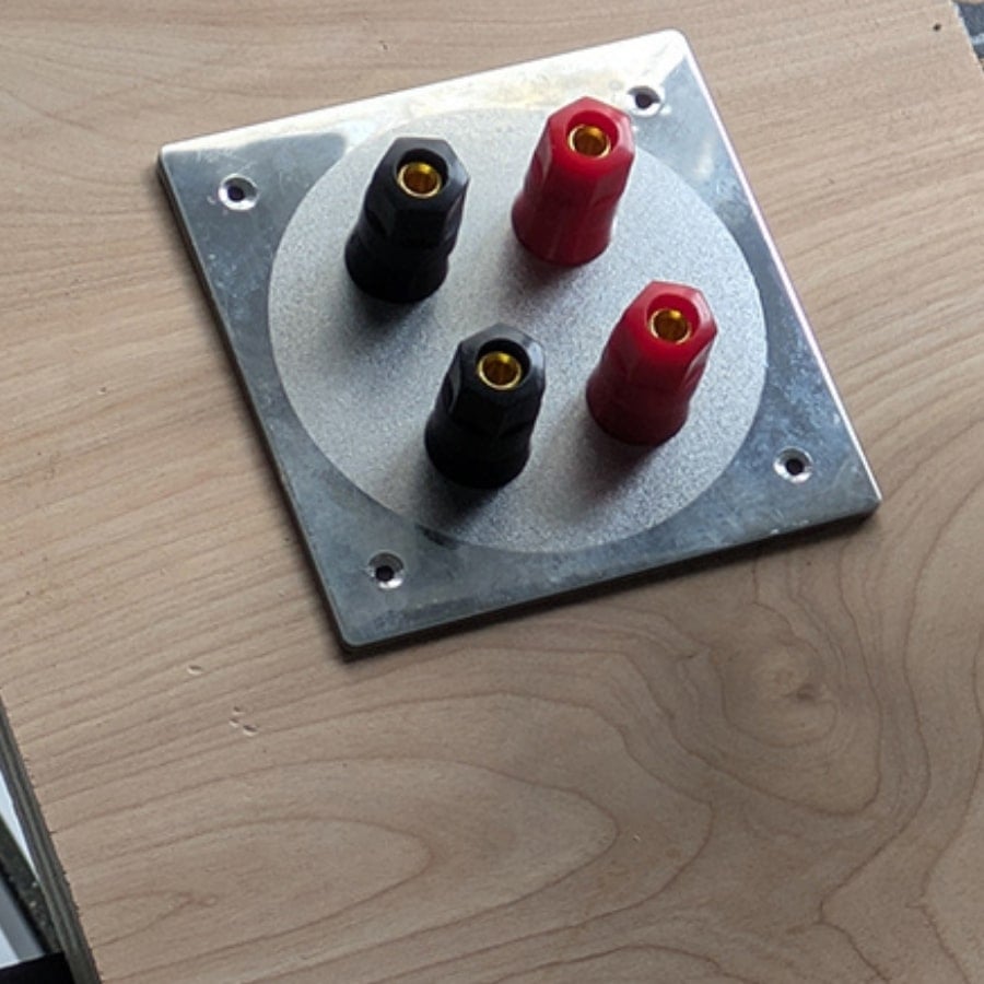 43 - IKEA Hackers Four banana binding posts (two red, two black) mounted on a metal square plate on a wooden surface.
