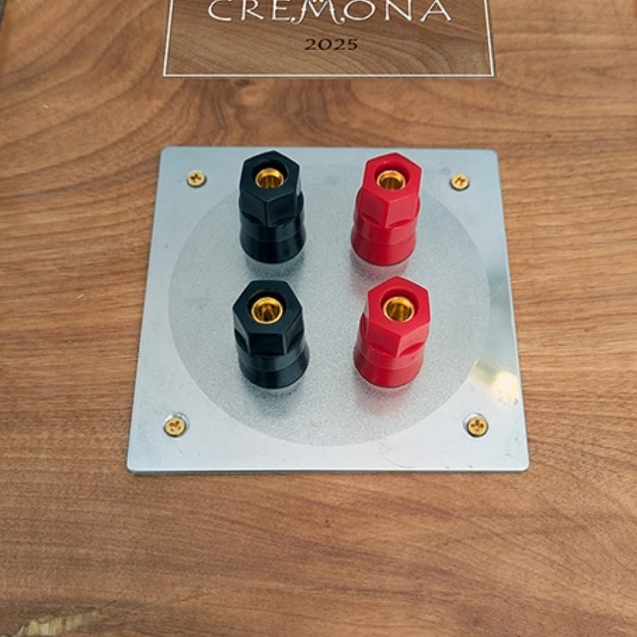 48 - IKEA Hackers Speaker binding posts on a metal plate with two red and two black connectors on a wooden surface; sign above reads CREMONA 2025.