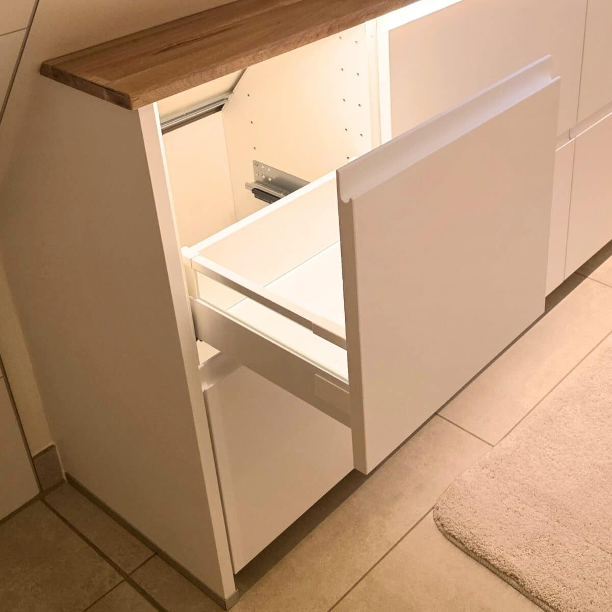 IKEA Kitchen cabinets cut to fit sloped ceilings. Drawer opened to show storage