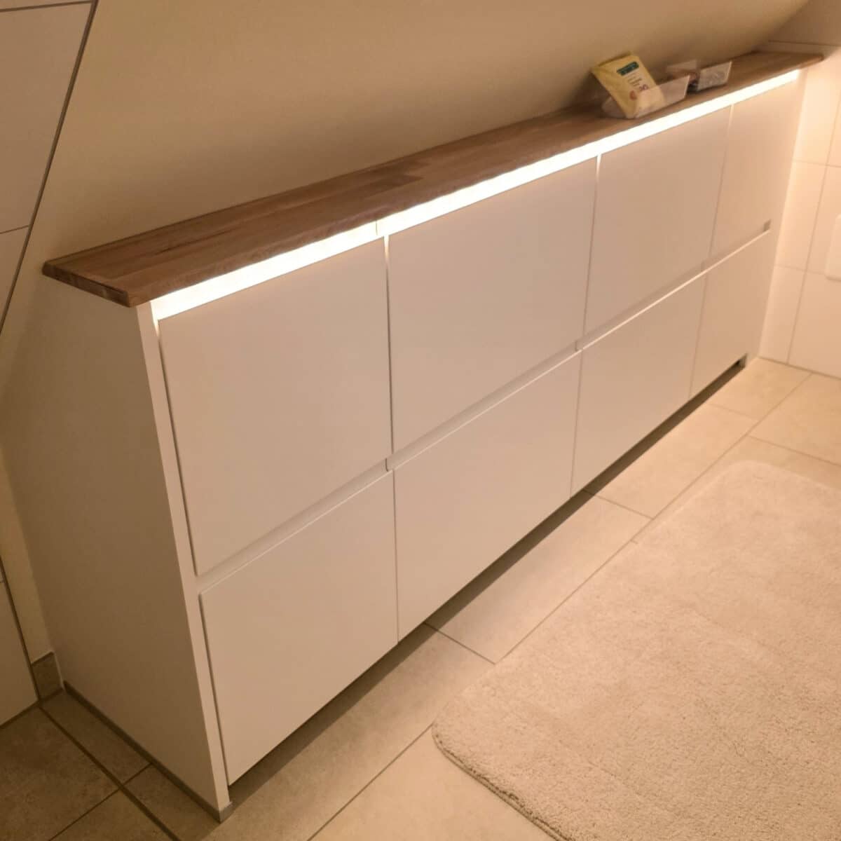 IKEA Kitchen cabinets cut to fit sloped ceilings with added LED lights under the top panel