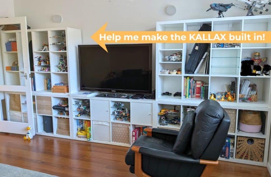 IKEA KALLAX shelving units - White modular shelves filled with toys, books and Lego under a mounted TV; a black leather recliner sits in front.